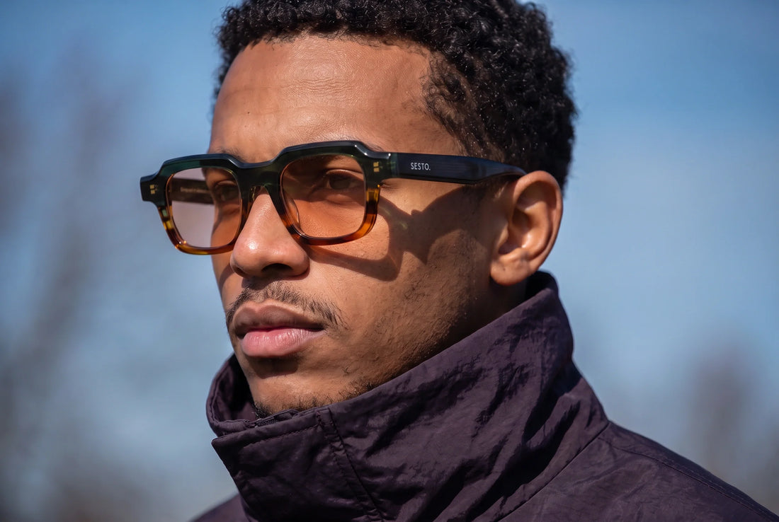 Junger Mann mit SESTO. ZENO Sonnenbrille im gruen-amber Zweiton-Acetat im Sommerlicht