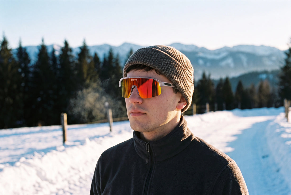 Mann mit SESTO. SOLE Sportbrille mit orange verspiegeltem Glas auf einem verschneiten Weg im Winterlicht