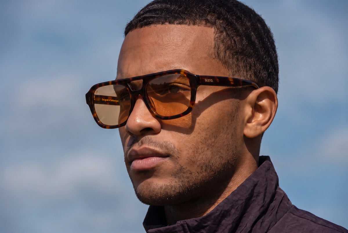 Junger Mann mit SESTO. AURA Sonnenbrille in Havana mit Doppelsteg und orangen Glaesern im Sommerlicht