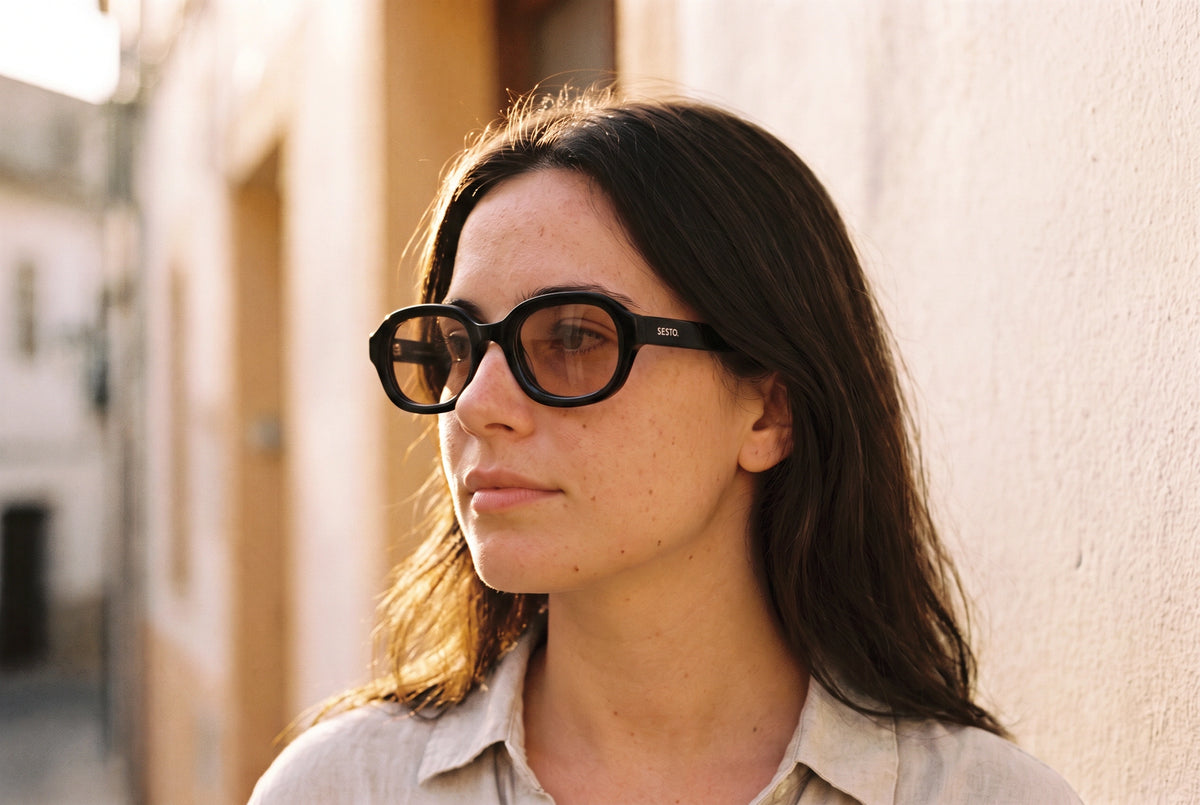 Junge Frau mit SESTO. RIVO Sonnenbrille im Profil an einer hellen Hauswand