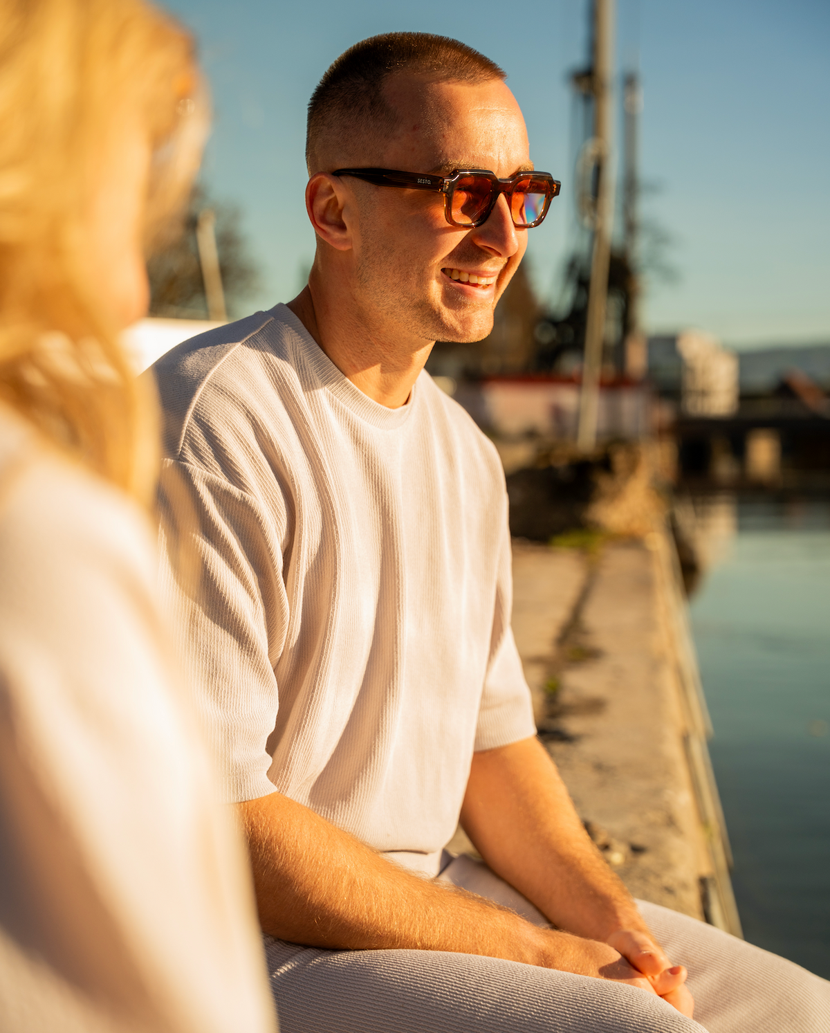 Mann mit SESTO. Sonnenbrille am Wasser im Abendlicht
